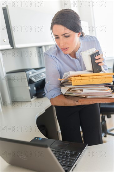 Business woman holding stack of documents and coffee cup.