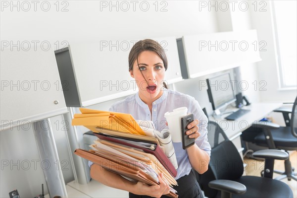 Business woman holding stack of documents in office.