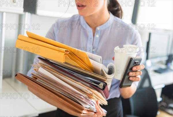 Business woman holding stack of documents in office.