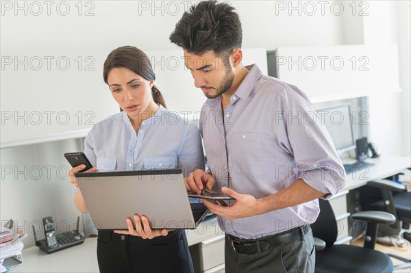 Businessman and businesswoman using technology in office.