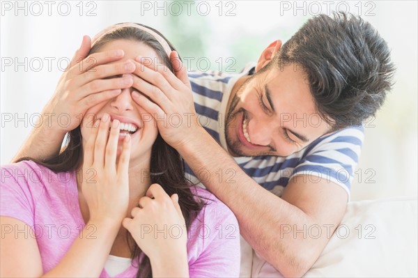 Man covering woman's eyes with his hands.