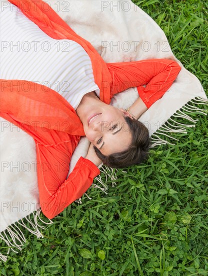 Mature woman lying on grass.