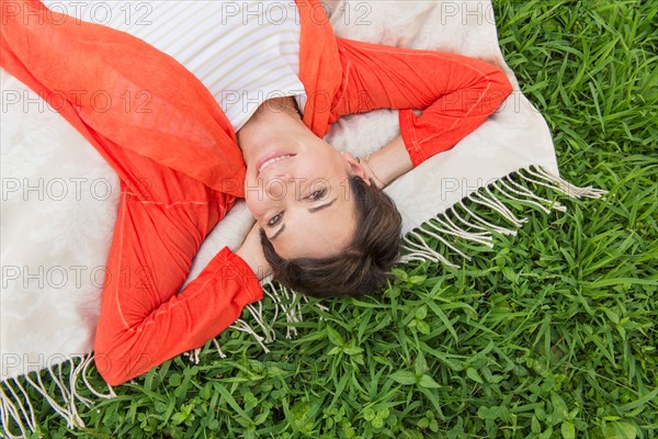 Mature woman lying on grass.