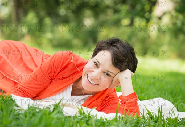 Mature woman lying on grass.