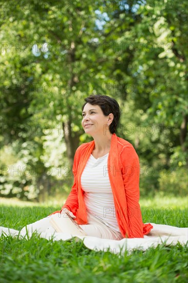 Mature woman sitting on grass in park.