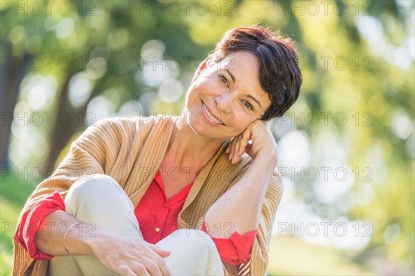 Mature woman sitting on grass in park.