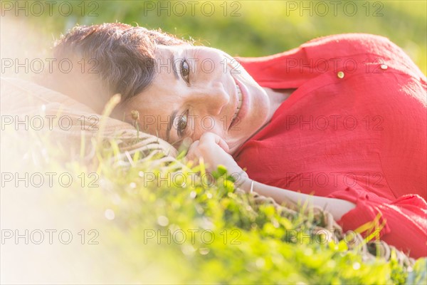 Mature woman lying on grass.