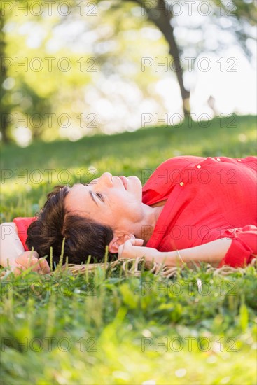 Mature woman lying on grass.