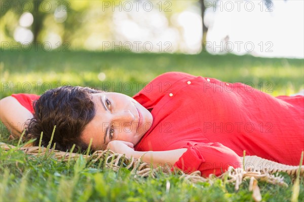 Mature woman lying on grass.