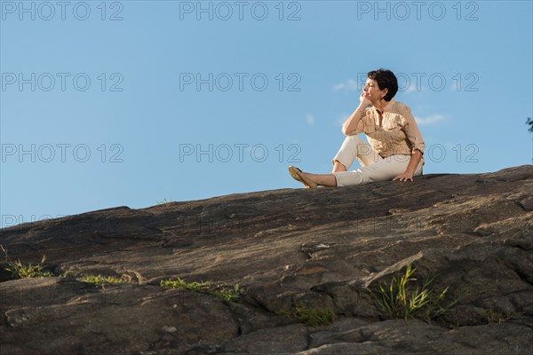 Mature woman sitting on rock.
