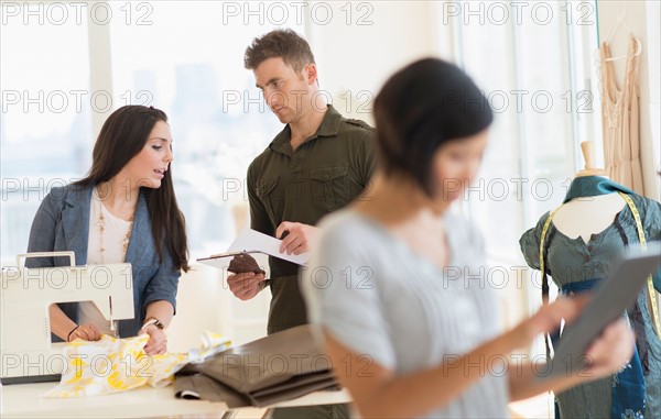 Three fashion designers working in studio.