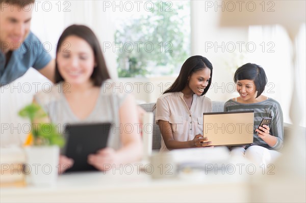 Women and man using laptop and digital tablet.