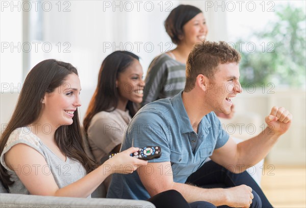 Friends watching tv on sofa.