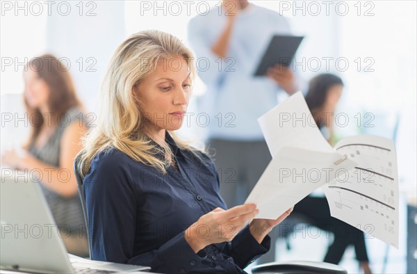 Woman reading at desk in office.