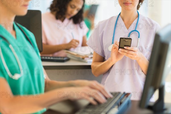 Doctors and nurses working at desks in hospital.