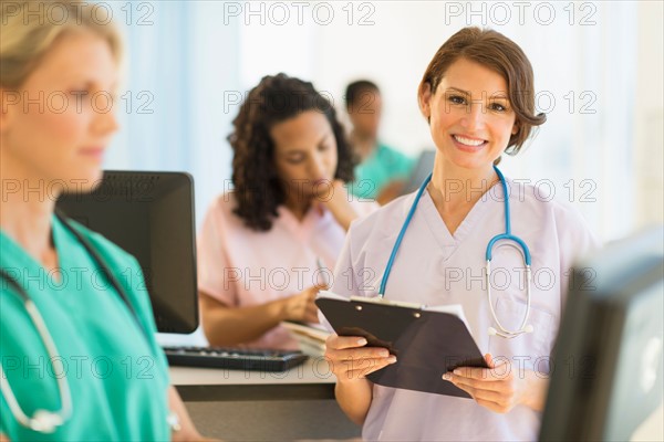 Doctors and nurses working at desks in hospital.