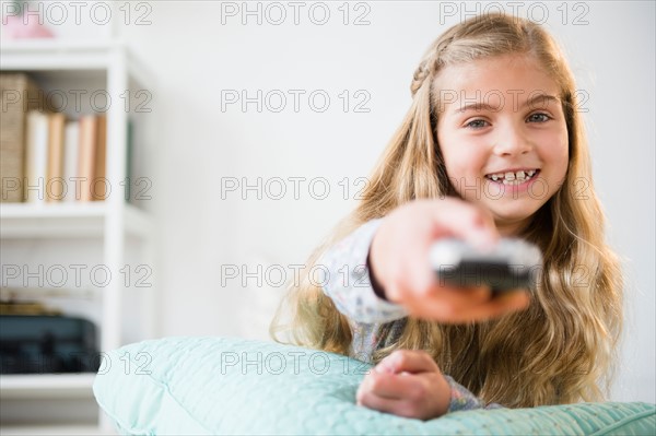 Girl (8-9) holding remote control