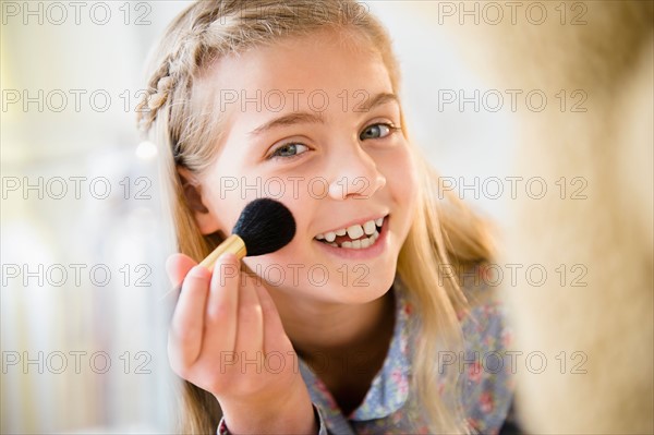 Girl (8-9) applying make-up