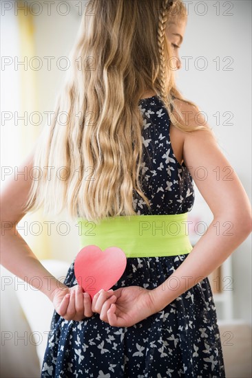 Rear view of girl (8-9) holding paper heart