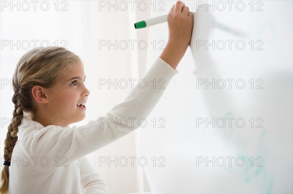 Portrait of girl (8-9) writing on white board