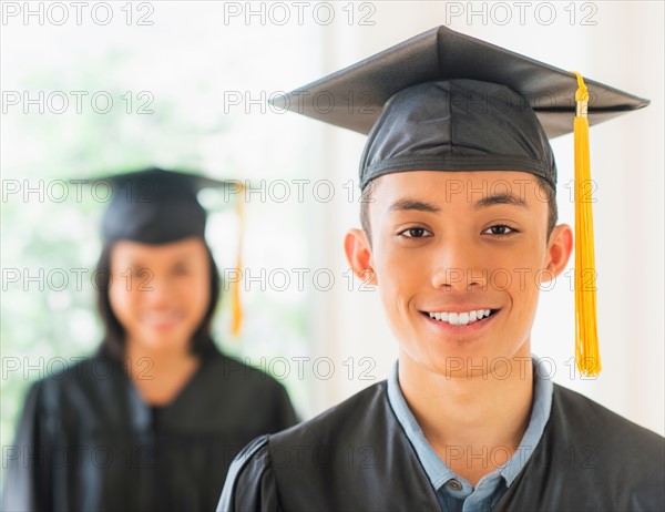 Portrait of young woman and young man wearing graduation gown