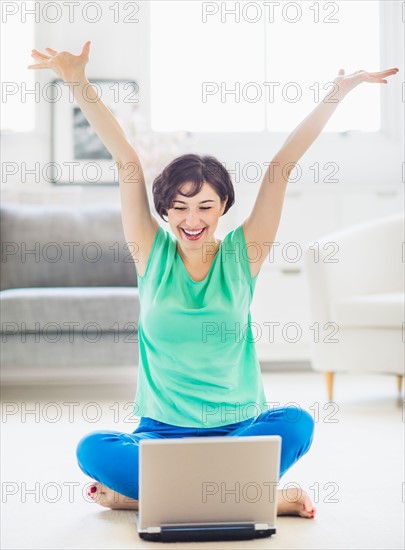 Young woman cheering in front of laptop