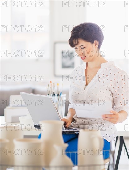 Portrait of woman in art studio using laptop