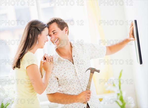 Portrait of happy couple hanging picture