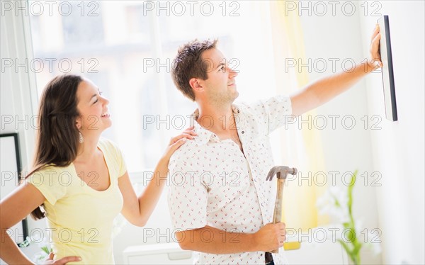 Portrait of happy couple hanging picture