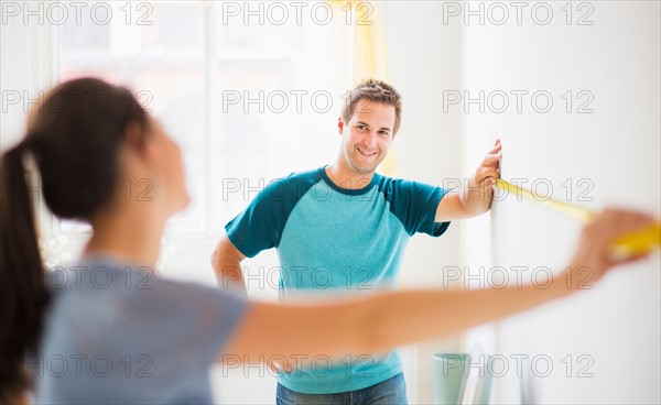 Couple measuring wall in their flat