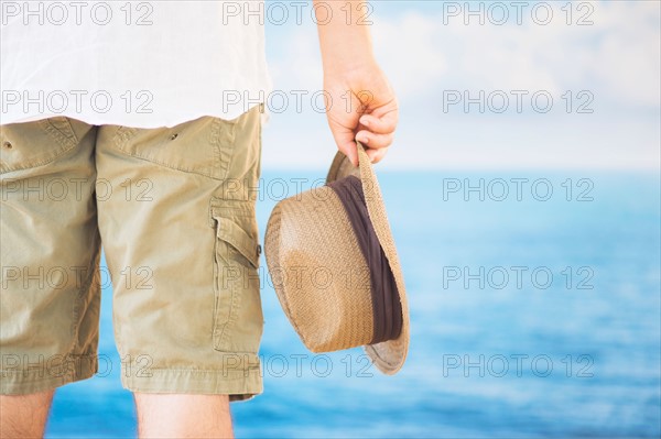 Studio Shot Rear view of man holding straw hat