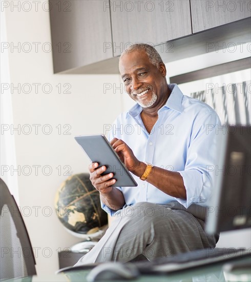 Portrait of senior man using digital tablet in office