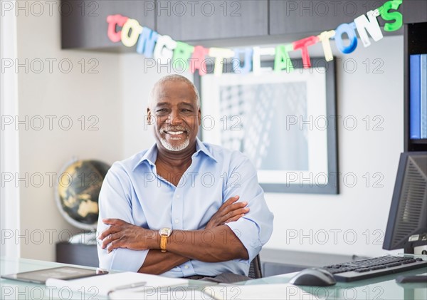 Portrait of man in office, congratulations sign behind