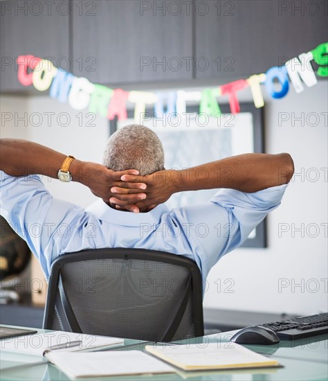 Rear view of man in office, congratulations sign in background