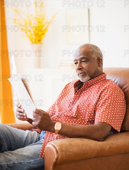 Portrait of men reading newspaper in armchair