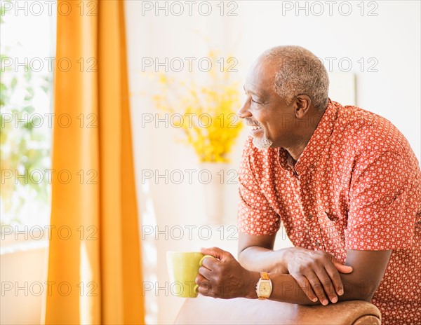 Portrait of men leaning on armchair, holding mug