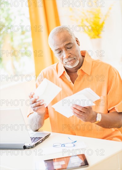 Portrait of man sorting mail at home