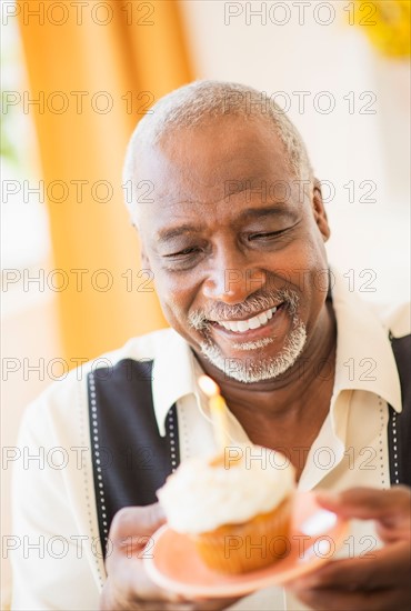 Portrait of man holding cupcake with candle