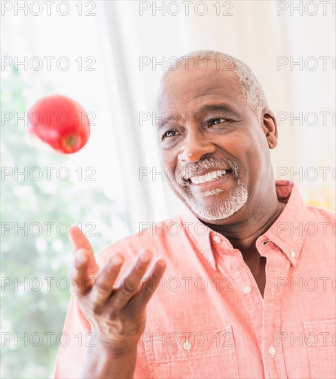 Portrait of man throwing red apple