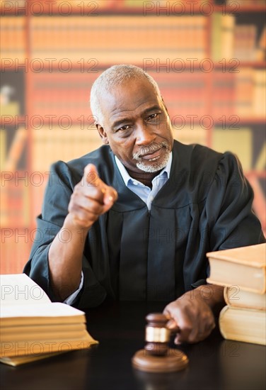 Judge holding gavel in courtroom and pointing