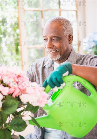 Portrait of man watering flowers in greenhouse