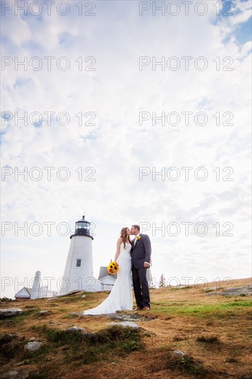 Portrait of married couple kissing, lighthouse in background