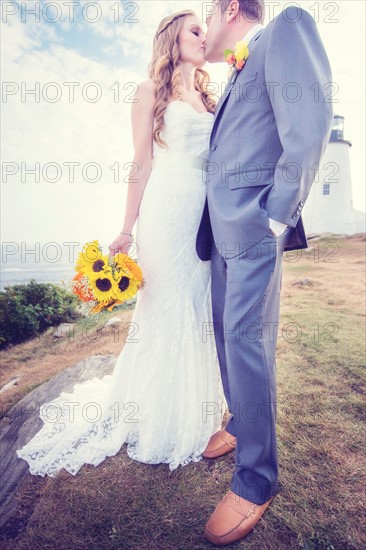 Portrait of married couple kissing, lighthouse in background