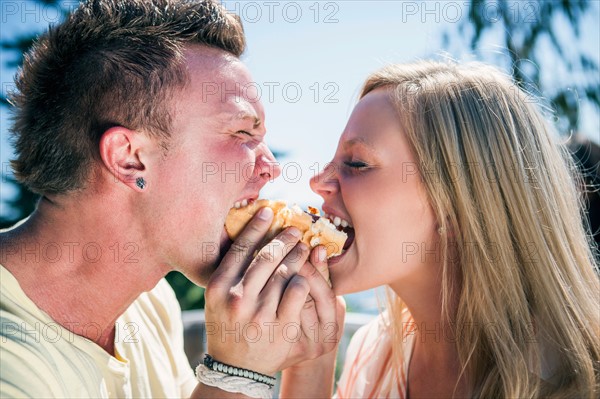 Young people eating one hot dog