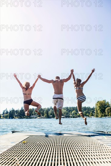 Young people jumping to lake from jetty