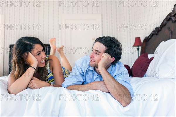 Young couple lying on bad in hotel room