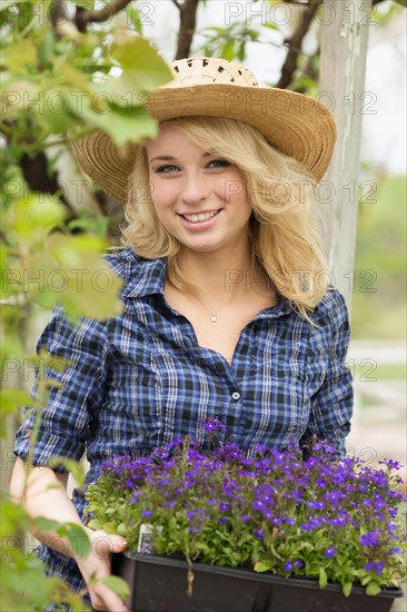 Portrait of young woman holding potted flowers