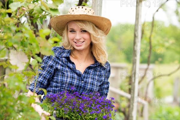 Portrait of young woman holding potted flowers