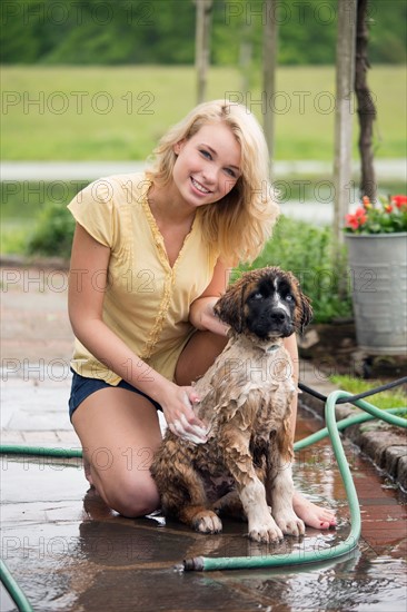 Portrait of young woman washing her dog