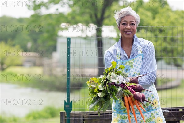 Portrait of senior woman holding carrots and beetroot